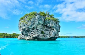 Vibrant turquoise waters and lush rock formations in Nouméa, New Caledonia.
